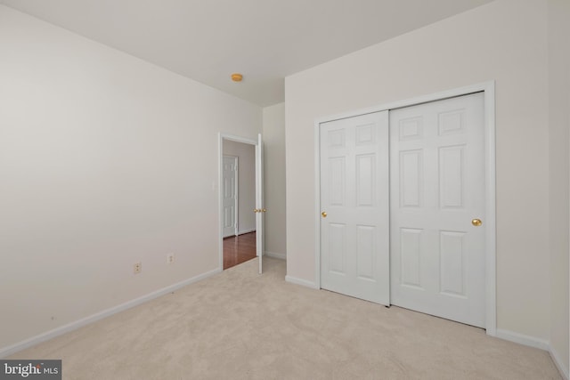 unfurnished bedroom featuring light carpet and a closet