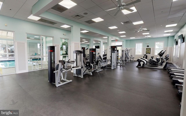 workout area featuring a drop ceiling, plenty of natural light, and ceiling fan