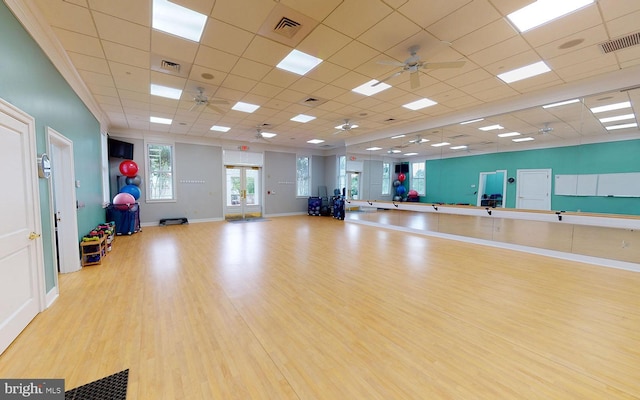 workout area featuring a paneled ceiling, ceiling fan, and light hardwood / wood-style flooring