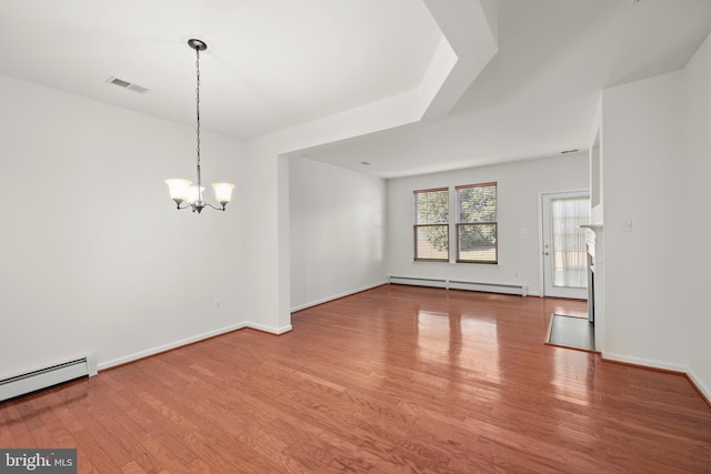 empty room featuring light hardwood / wood-style flooring, a notable chandelier, and a baseboard heating unit