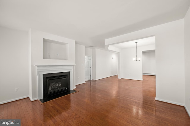 unfurnished living room featuring a chandelier, wood-type flooring, and a baseboard heating unit