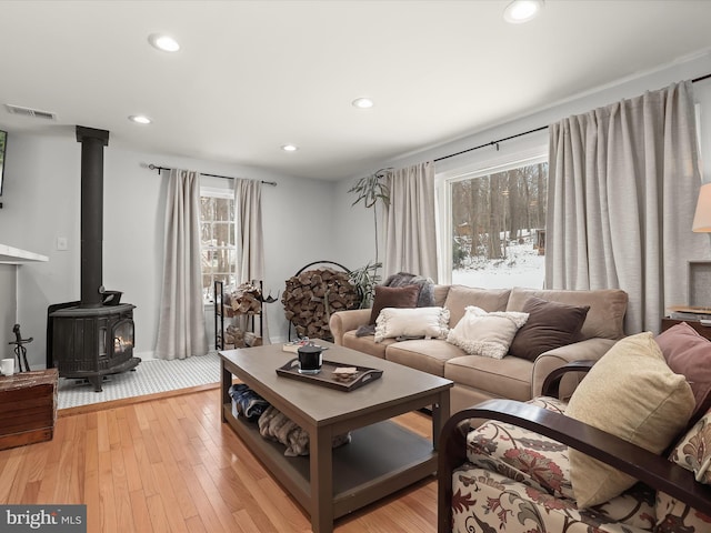 living room with light hardwood / wood-style floors and a wood stove