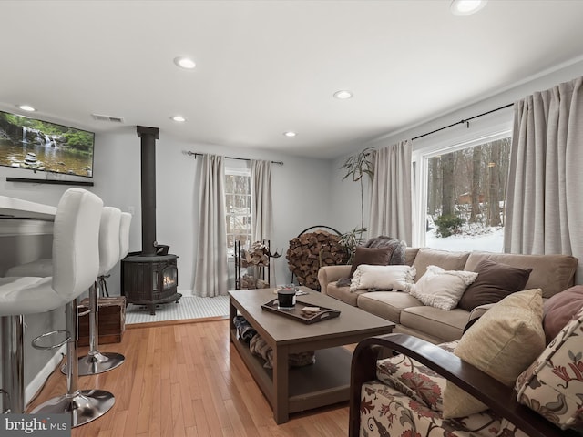 living room with light hardwood / wood-style floors and a wood stove