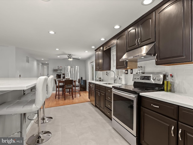 kitchen featuring stainless steel appliances, ceiling fan, sink, dark brown cabinets, and tasteful backsplash