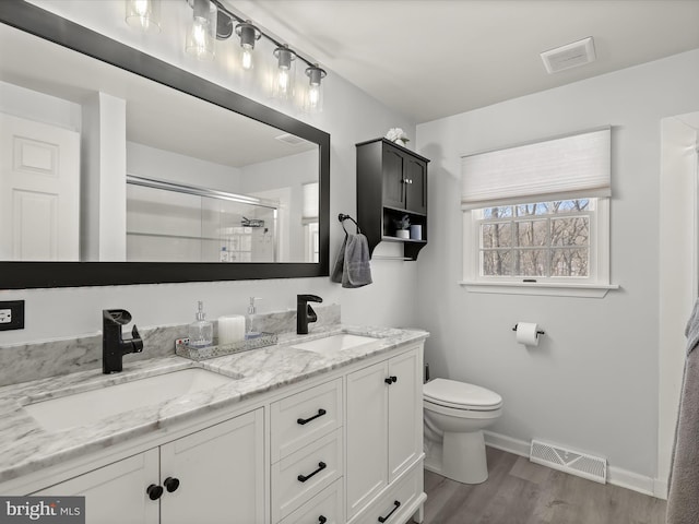 bathroom with toilet, walk in shower, vanity, and hardwood / wood-style floors