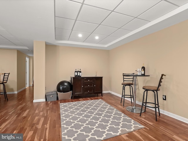 living area with wood-type flooring, a raised ceiling, and bar area