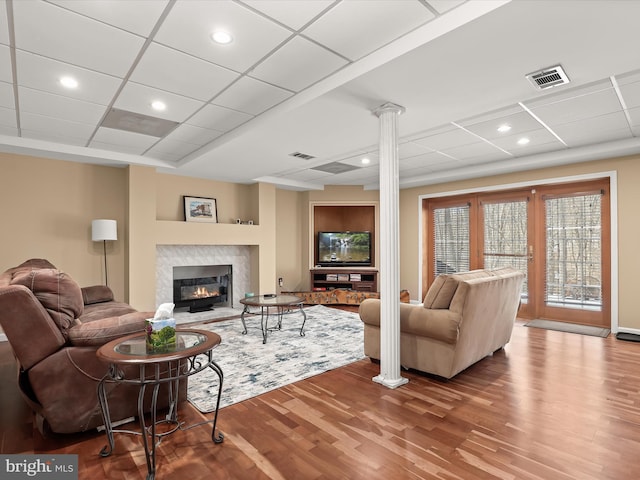 living room featuring ornate columns, a tile fireplace, and hardwood / wood-style flooring