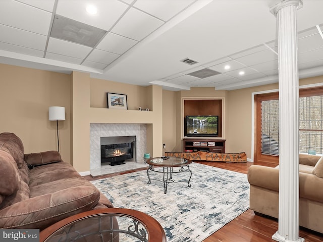 living room with a fireplace, decorative columns, a paneled ceiling, and hardwood / wood-style floors