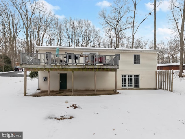 snow covered house featuring french doors and a deck