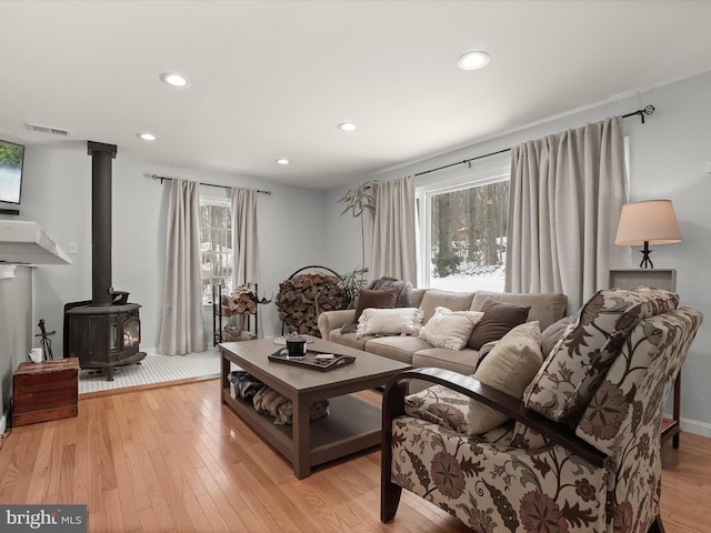 living room with a healthy amount of sunlight, light hardwood / wood-style flooring, and a wood stove