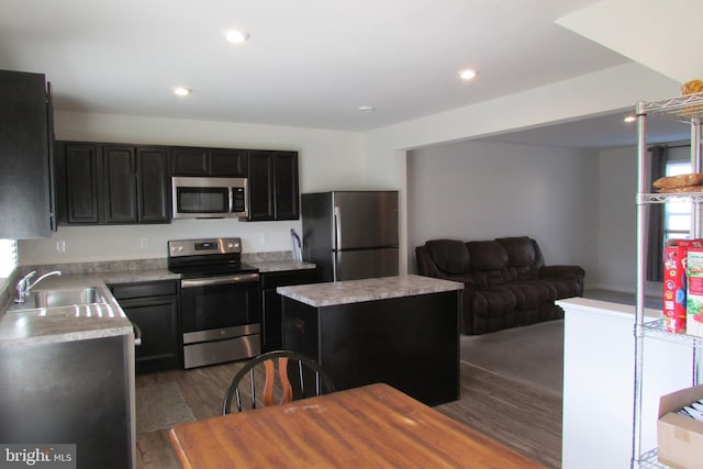 kitchen featuring dark hardwood / wood-style flooring, a center island, stainless steel appliances, and sink