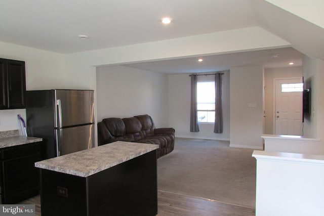 kitchen featuring plenty of natural light, a center island, light colored carpet, and stainless steel refrigerator