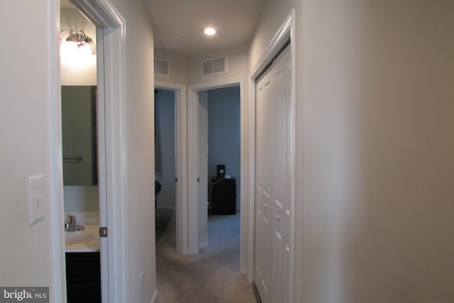 corridor featuring light colored carpet and sink