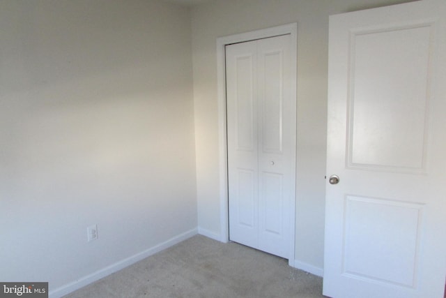 unfurnished bedroom with light carpet and a closet