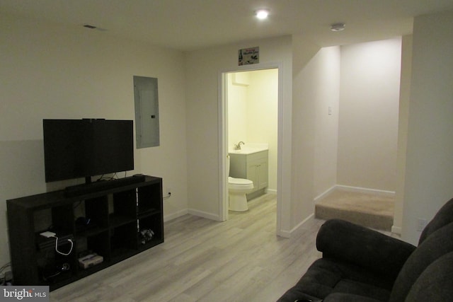 living room featuring sink, electric panel, and light hardwood / wood-style flooring