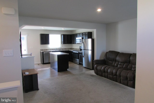 kitchen with appliances with stainless steel finishes, light hardwood / wood-style floors, and a kitchen island