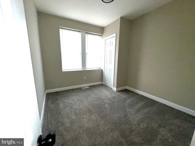 spare room with dark carpet