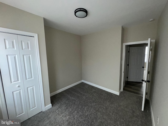 unfurnished bedroom featuring dark carpet and a closet