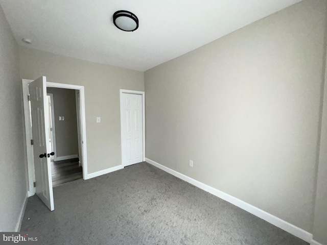 unfurnished bedroom with dark carpet and a closet