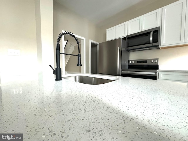 kitchen featuring white cabinetry, stainless steel appliances, sink, and light stone counters