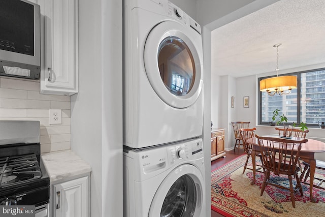 3701 S George Mason Dr Unit 1005N, Falls Church, VA 22041 - laundry room featuring laundry area, a textured ceiling, a chandelier, wood finished floors, and stacked washer and clothes dryer
