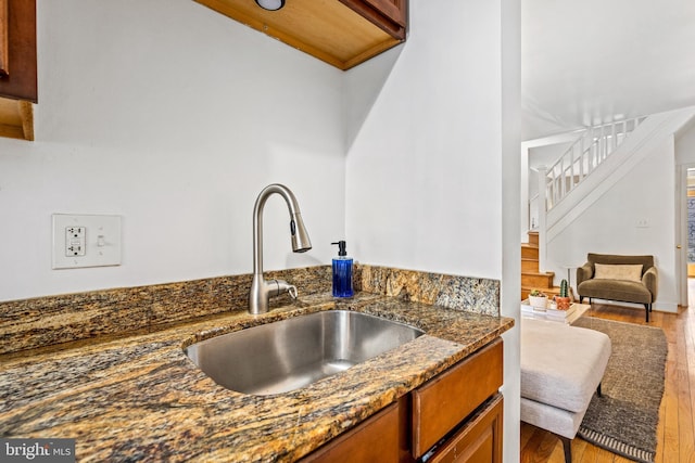 kitchen with dark stone counters, sink, and light hardwood / wood-style flooring