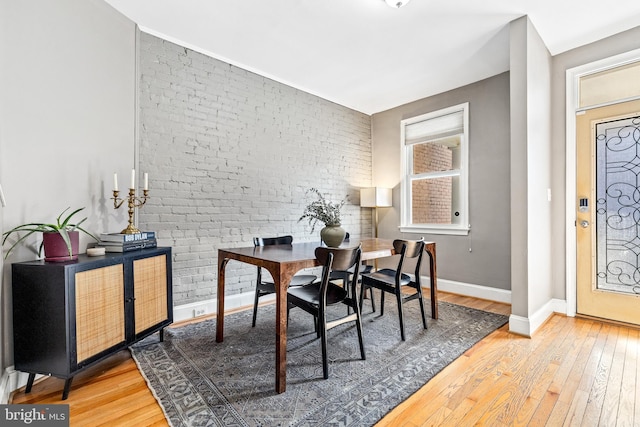 dining space featuring hardwood / wood-style floors and brick wall