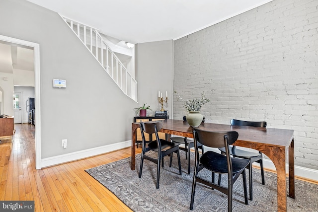 dining room with wood-type flooring and brick wall