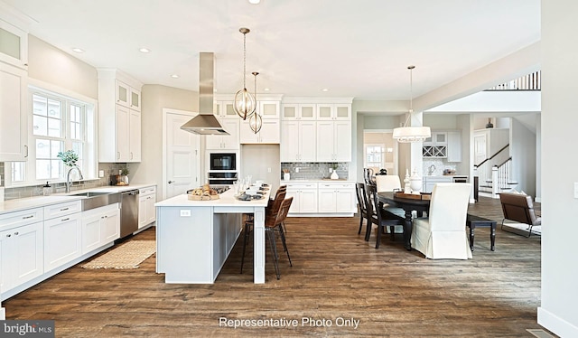 kitchen with a center island, island range hood, white cabinets, and pendant lighting