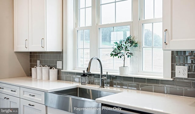 kitchen with white cabinets, sink, and tasteful backsplash