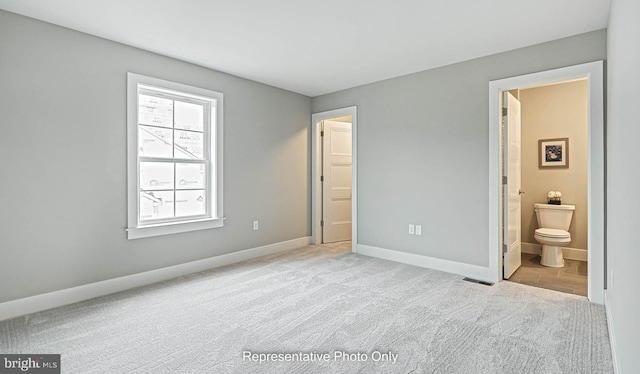 unfurnished bedroom with light carpet and connected bathroom