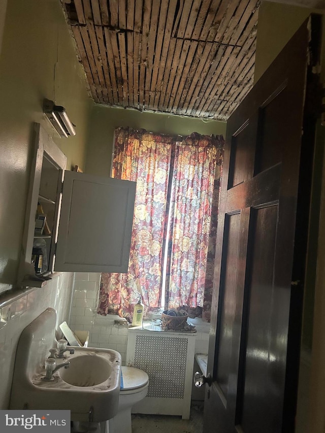 bathroom featuring concrete flooring, toilet, radiator, and sink