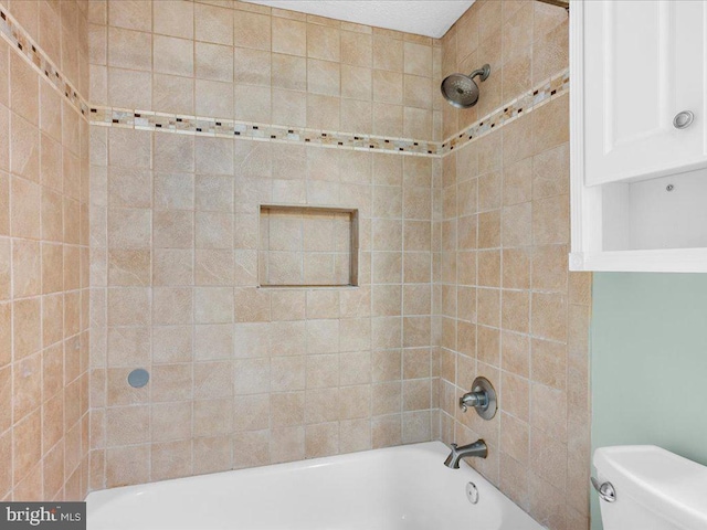 bathroom featuring toilet and tiled shower / bath