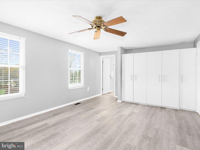 unfurnished bedroom with a closet, ceiling fan, light hardwood / wood-style flooring, and a textured ceiling