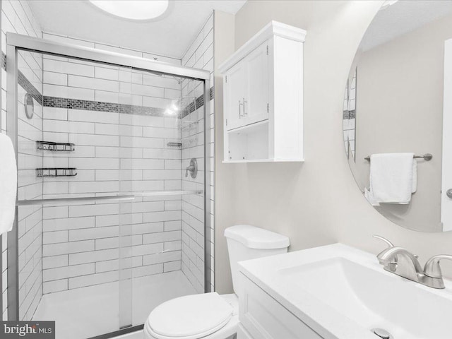 bathroom featuring vanity, a shower with shower door, and toilet