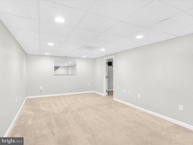 basement featuring a drop ceiling and light colored carpet