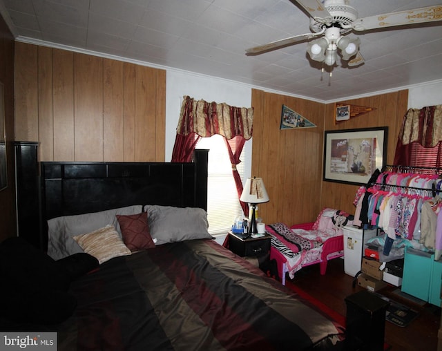 bedroom with ceiling fan, wood walls, and crown molding