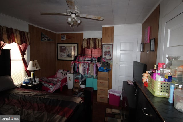 bedroom with wooden walls, ceiling fan, and ornamental molding