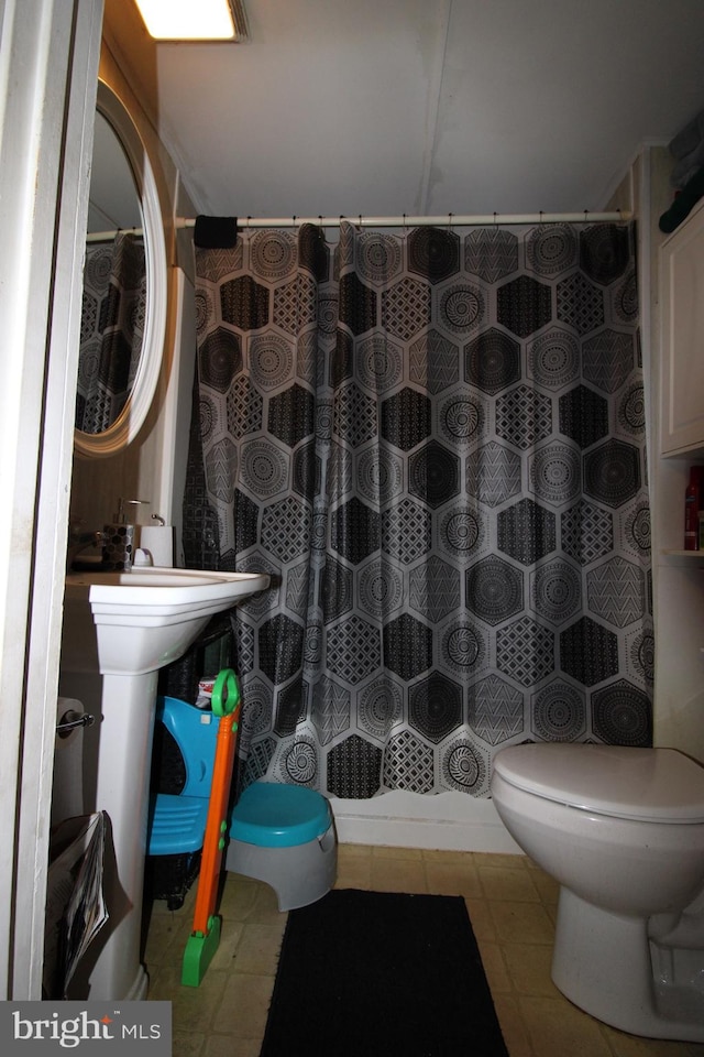 bathroom with curtained shower, tile patterned flooring, and toilet