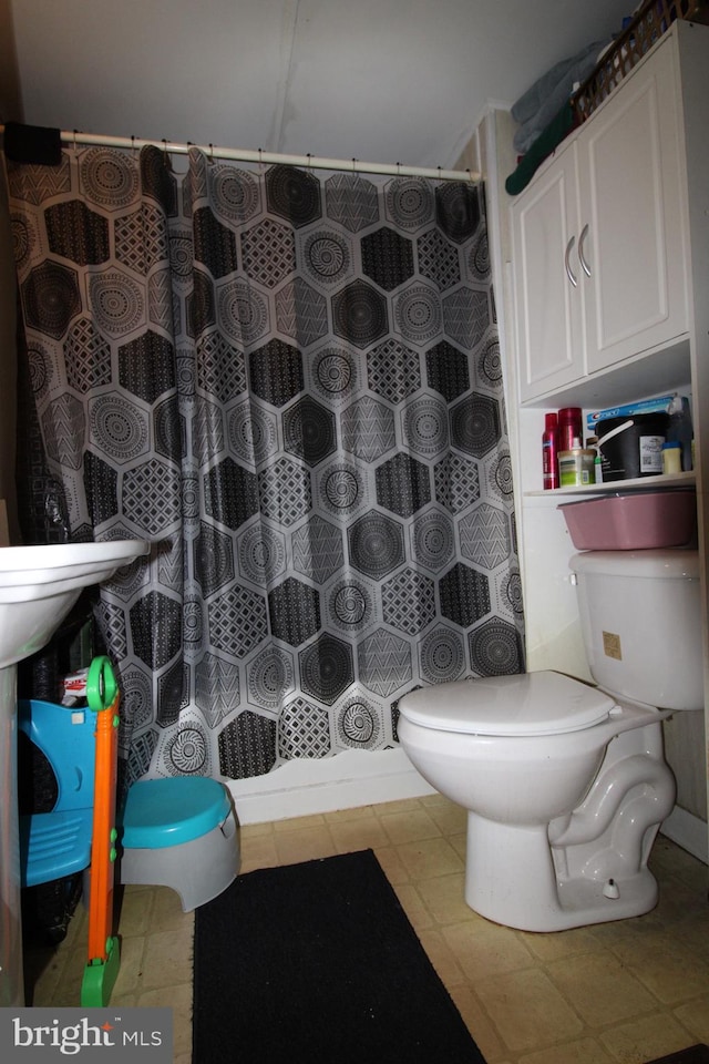 bathroom with tile patterned flooring, curtained shower, and toilet