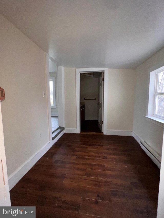 empty room featuring dark wood-type flooring and a baseboard radiator