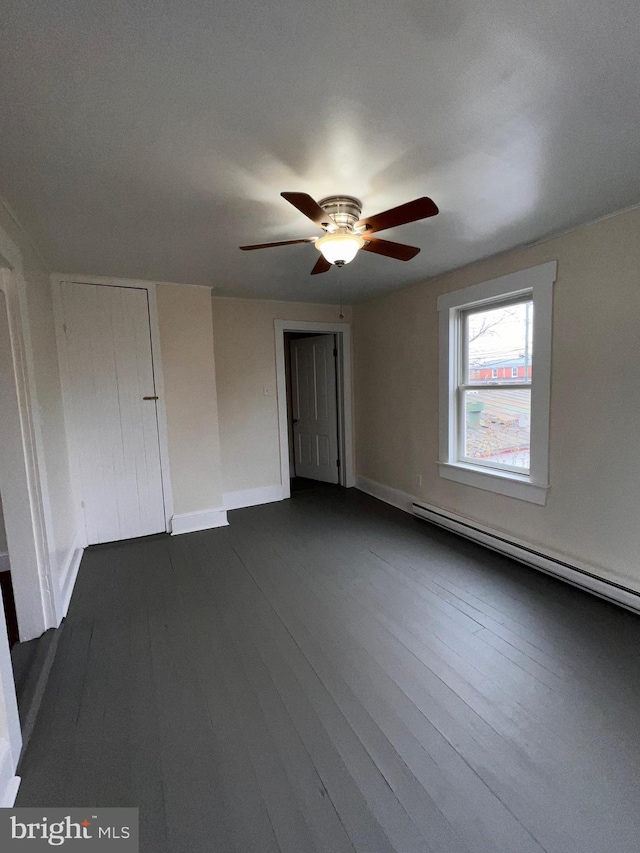 empty room with ceiling fan, baseboard heating, and dark wood-type flooring