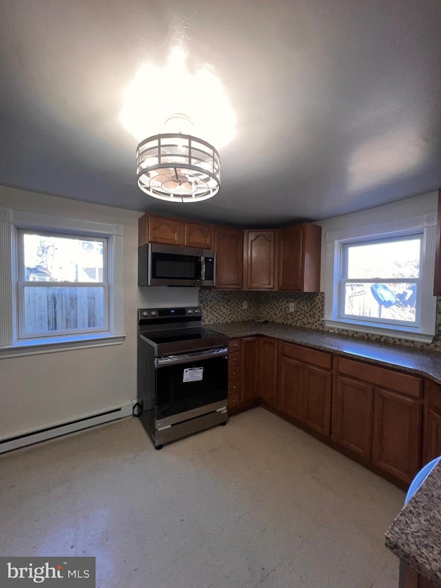 kitchen featuring appliances with stainless steel finishes, backsplash, a baseboard radiator, and a healthy amount of sunlight