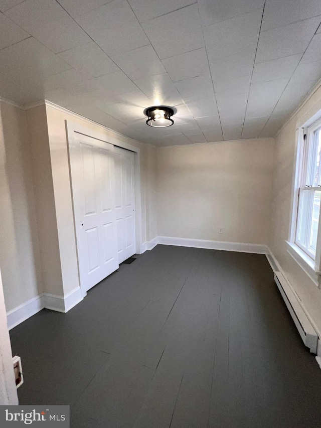 spare room featuring a baseboard radiator and dark wood-type flooring