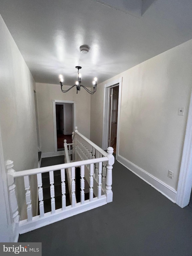 stairs with concrete floors and an inviting chandelier