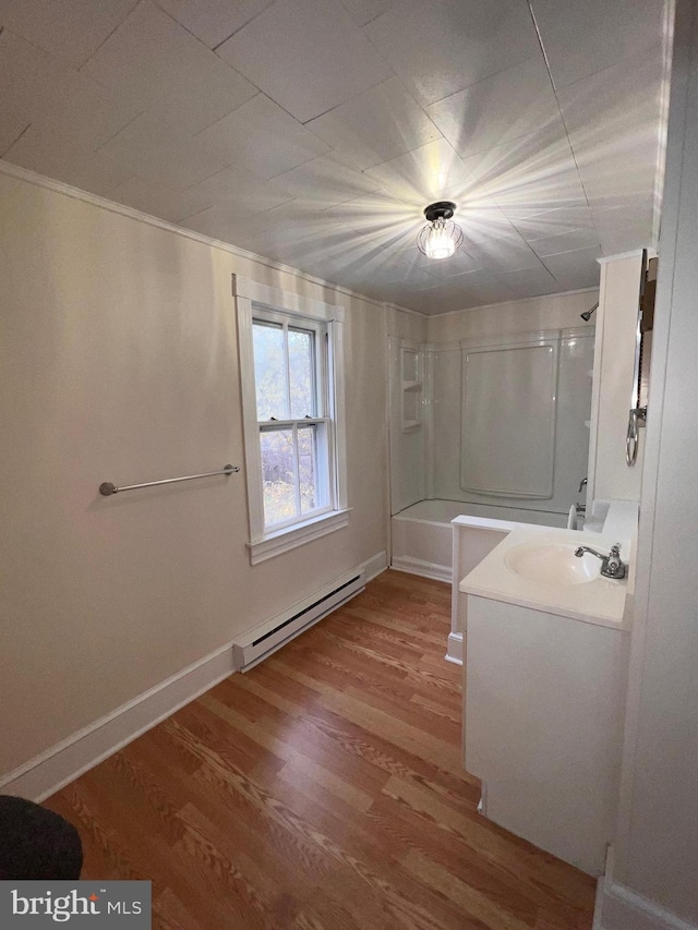 bathroom with vanity, wood-type flooring,  shower combination, and a baseboard heating unit