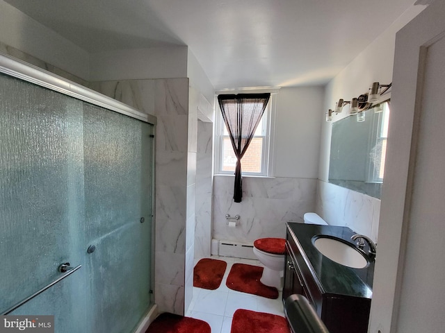 bathroom with vanity, a shower with door, tile patterned flooring, tile walls, and a baseboard radiator