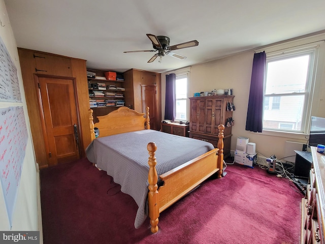 bedroom featuring multiple windows, dark colored carpet, and ceiling fan