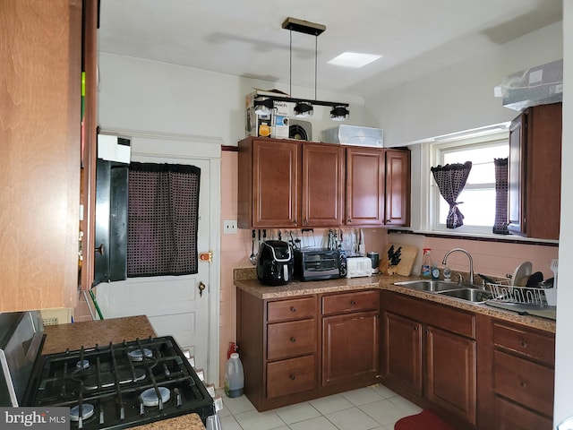 kitchen featuring sink, tasteful backsplash, black range with gas cooktop, pendant lighting, and light tile patterned floors