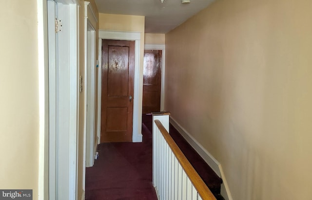 hallway featuring dark colored carpet